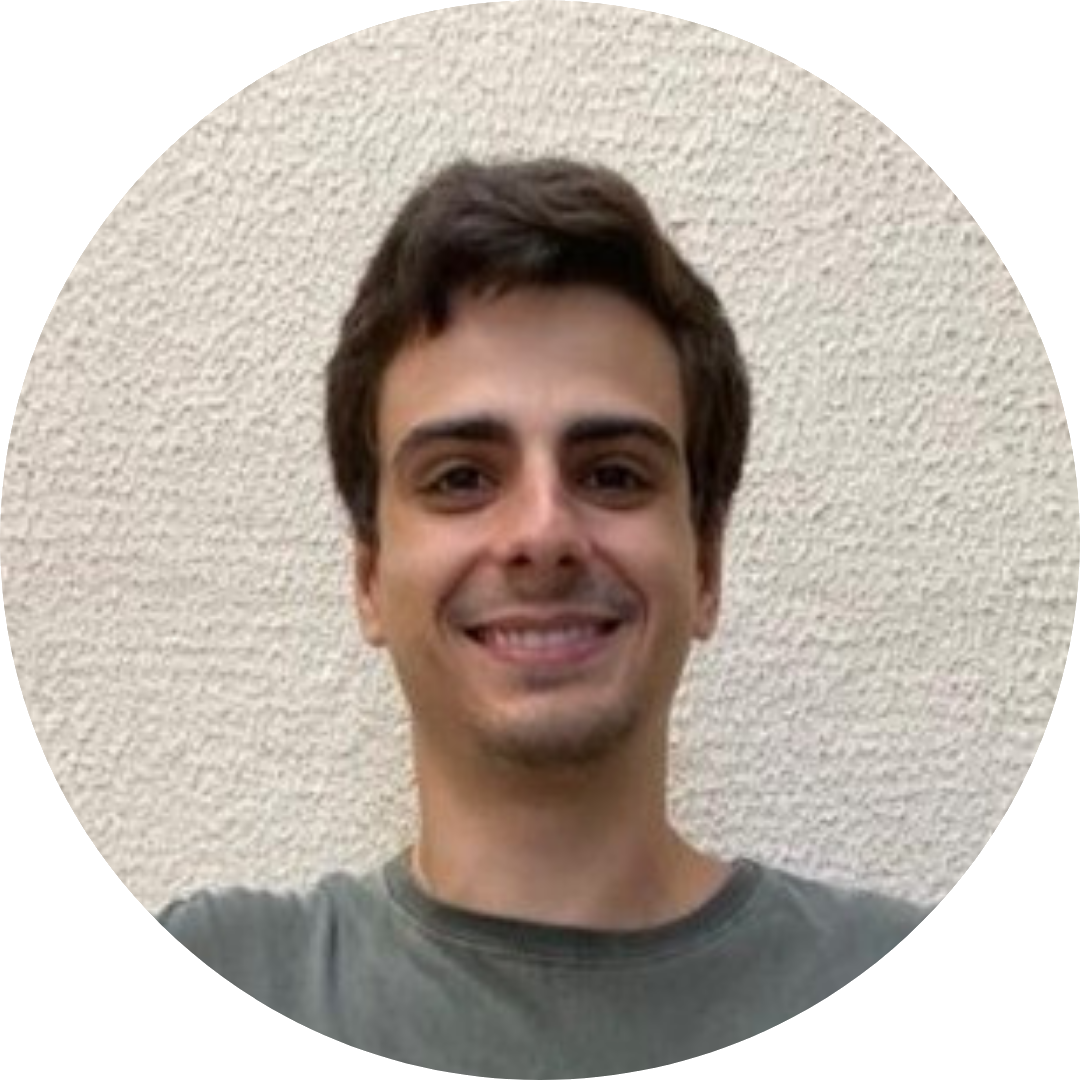 Foto de Filipe Brega Có Silva sorrindo, usando camisa cinza, com fundo bege